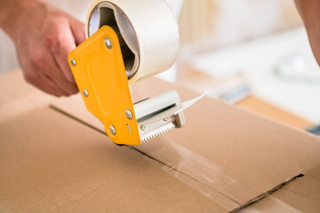 A closeup photo of a man's hand and a packing tape