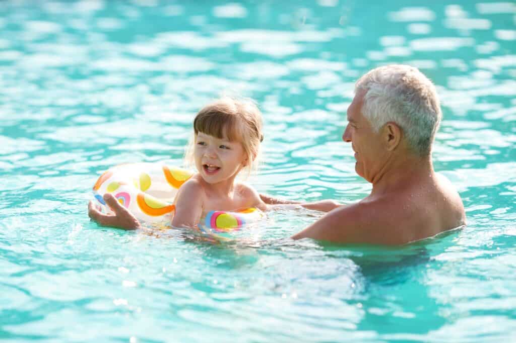 A grandfather and granddaughter swimming in the pool in the concept of ' top services and amenities in Fulham'.